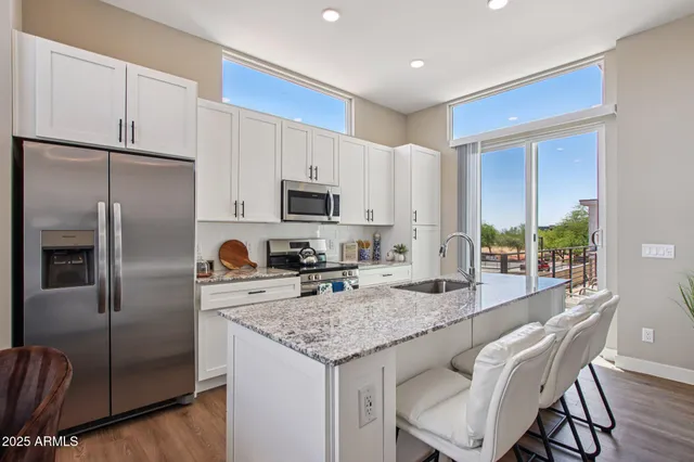 a large kitchen with stainless steel appliances granite countertop a stove a sink dishwasher a dining table and chairs with wooden floor