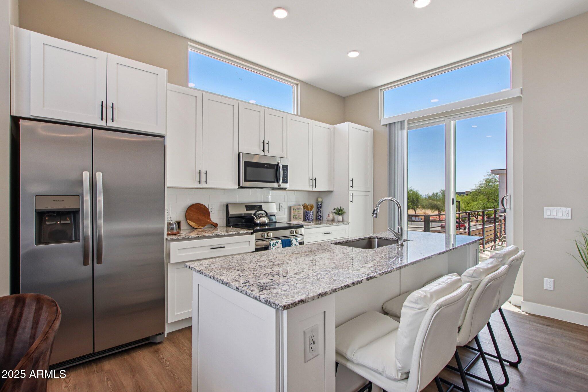 1927 South Recker Road, Unit 175 Mesa, AZ 85206 - Photo 11 of 34 a kitchen with kitchen island granite countertop a refrigerator a stove a sink a dining table and chairs