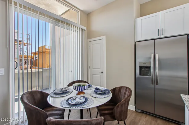 a kitchen with stainless steel appliances granite countertop a dining table chairs refrigerator and sink