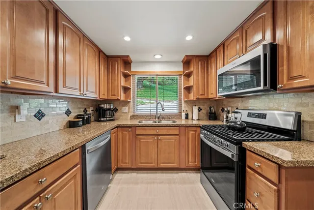a kitchen with stainless steel appliances granite countertop a stove sink microwave and cabinets