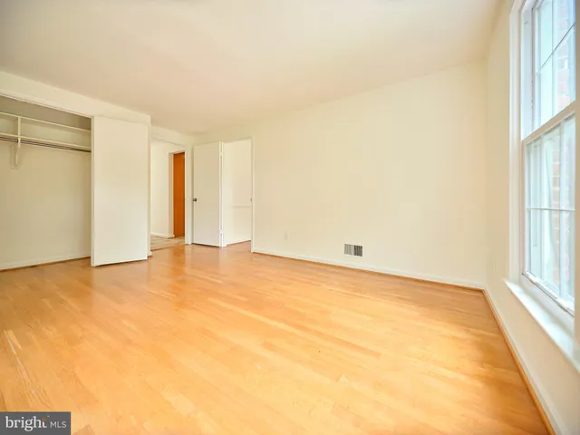 an empty room with wooden floor chandelier and windows