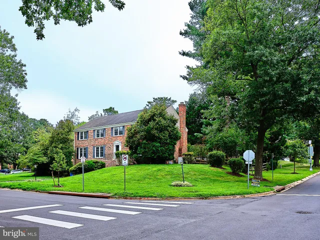 a view of a house with a big yard and large trees