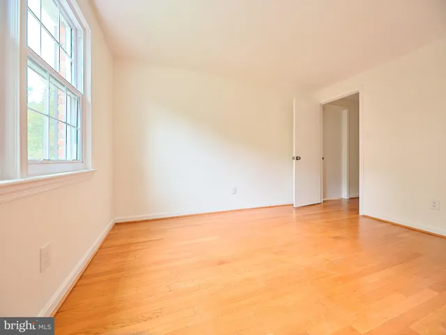 an empty room with wooden floor and natural light