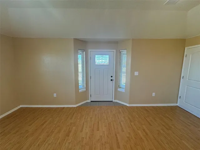 a view of an empty room with wooden floor and closet
