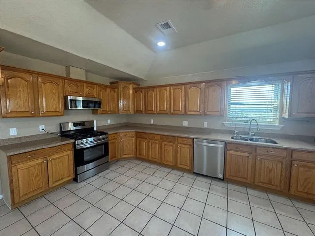 a large kitchen with granite countertop a stove top oven microwave and cabinets