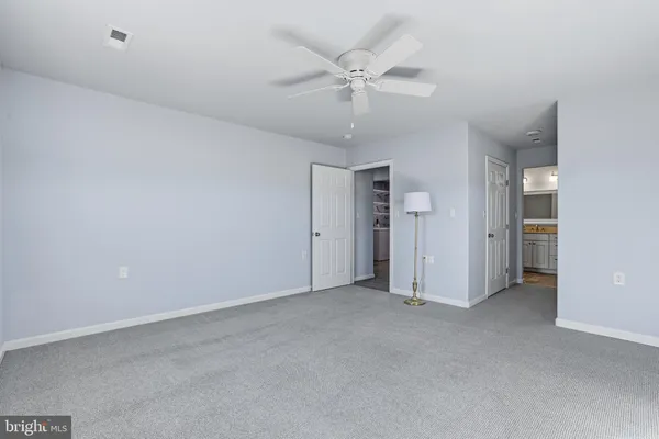 an empty room with closet and a ceiling fan