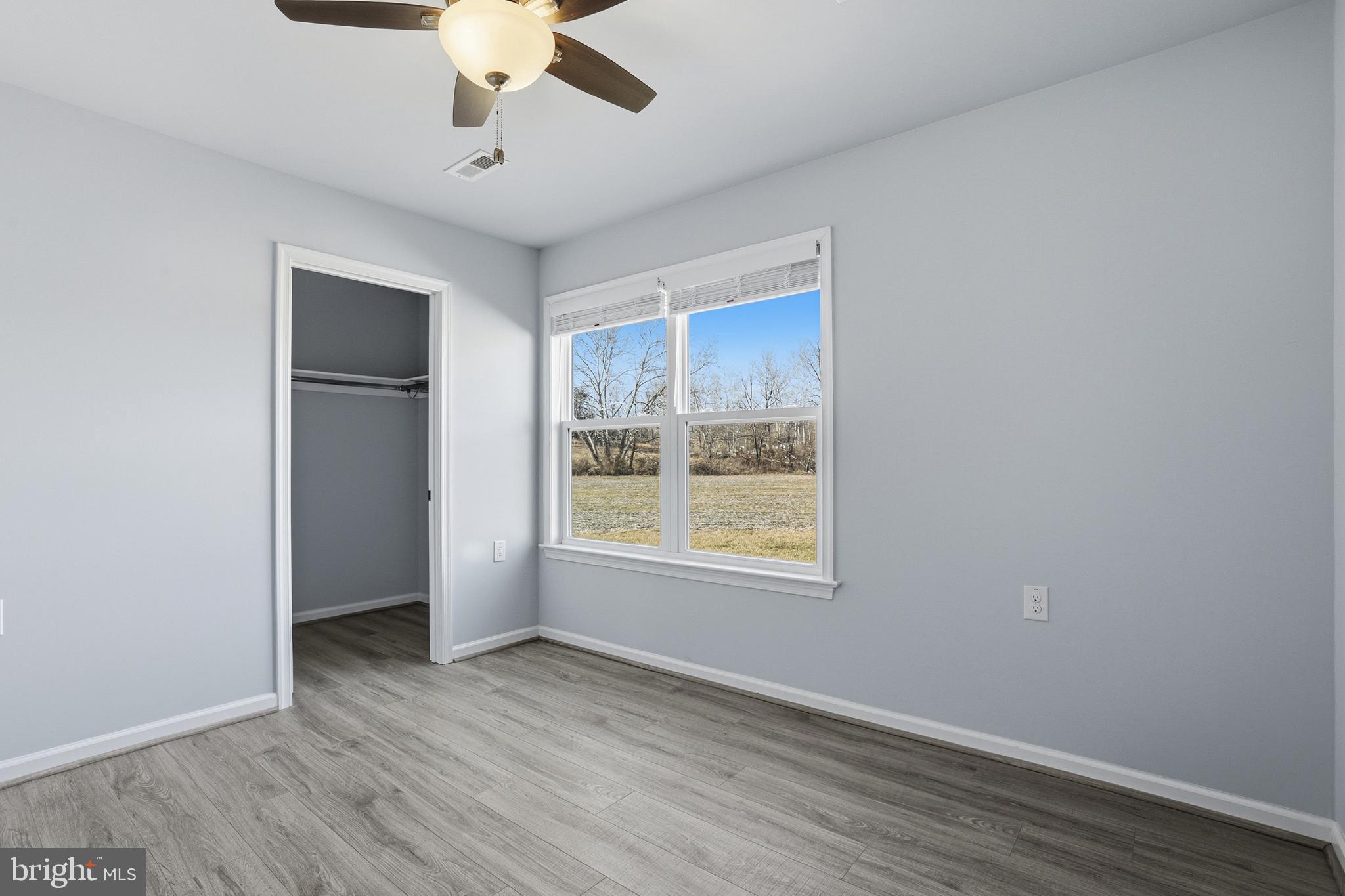 5810 West Hoover Road Reva, VA 22735 - Photo 19 of 25 an empty room with wooden floor chandelier fan and windows