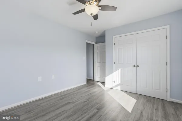 a view of an empty room with wooden floor and a ceiling fan