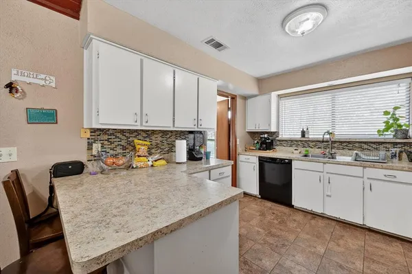 a kitchen with granite countertop a sink chairs and cabinets
