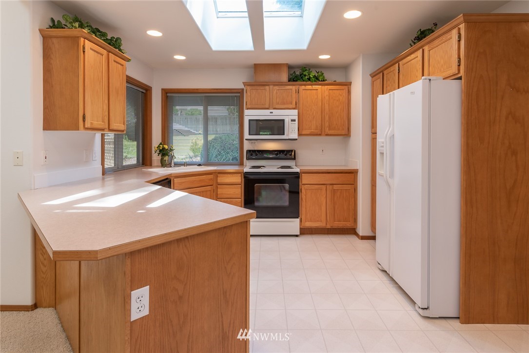 5203 53rd Street West University Place, WA 98467 - Photo 9 of 35 a kitchen with stainless steel appliances granite countertop a refrigerator a stove and a sink with wooden floor
