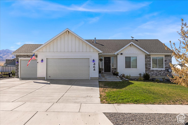 464 South Trejo Rdg Road Grantsville, UT 84029 - Photo 2 of 33 Ranch-style home with board and batten siding, a front lawn, a garage, concrete driveway, and roof with shingles