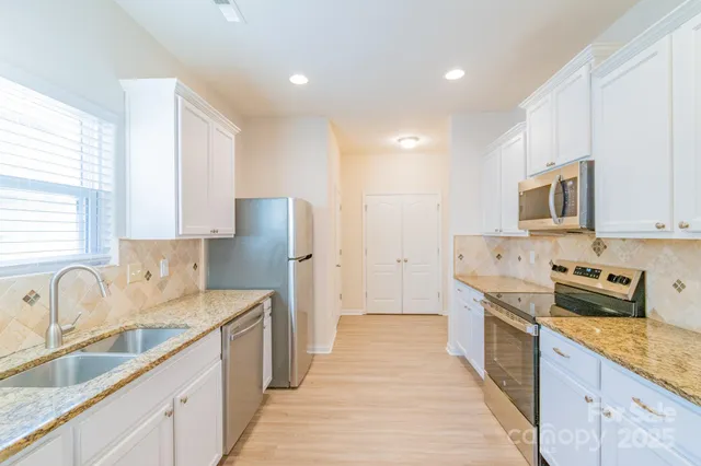 a kitchen with stainless steel appliances granite countertop a sink stove and refrigerator