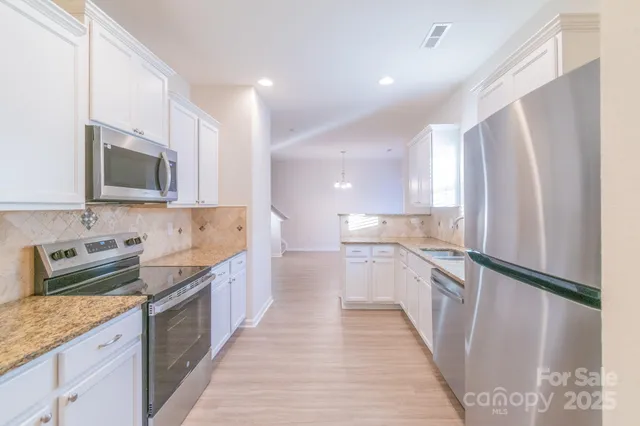 a kitchen with stainless steel appliances granite countertop a refrigerator a stove top oven a sink and dishwasher