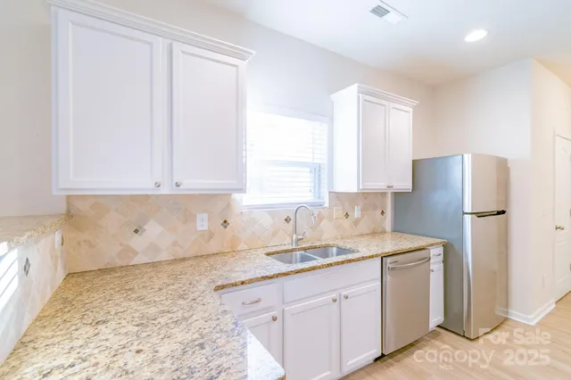 a kitchen with stainless steel appliances granite countertop a refrigerator sink and white cabinets
