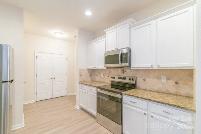 a kitchen with stainless steel appliances granite countertop a stove a sink and a microwave