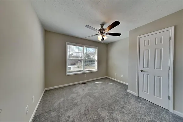an empty room with windows and ceiling fan