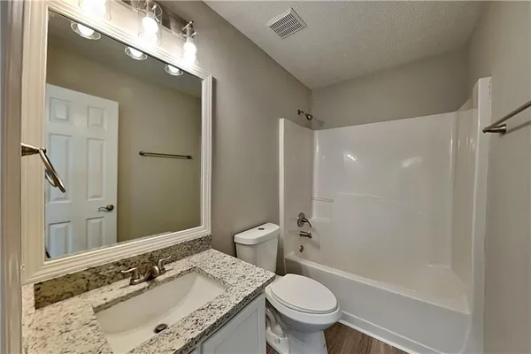a bathroom with a granite countertop sink toilet and shower