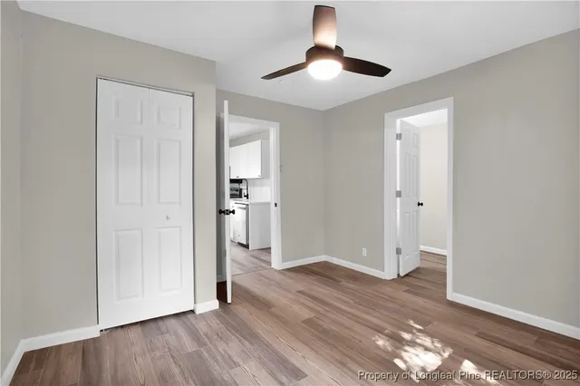 an empty room with wooden floor closet and windows