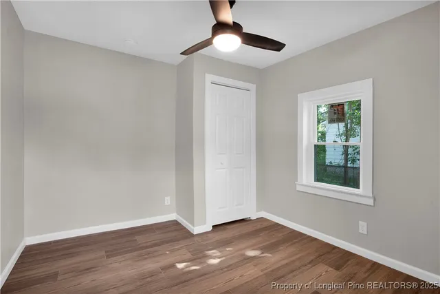 a view of an empty room with wooden floor and a window