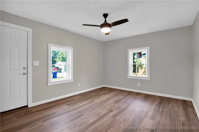 a view of empty room with wooden floor and fan