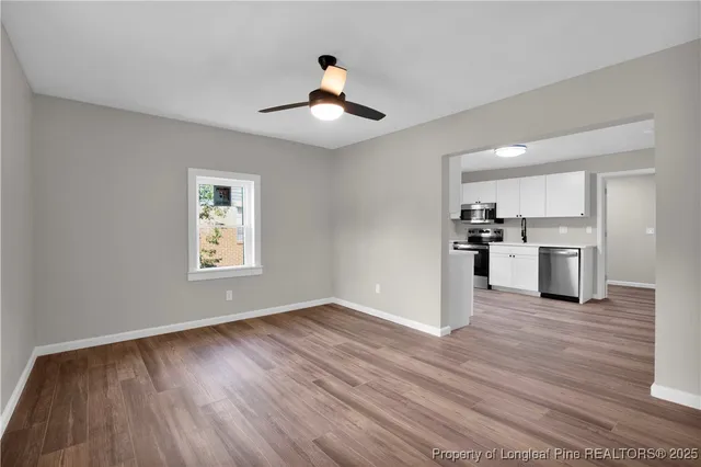 a view of a kitchen with wooden floor a ceiling fan and windows