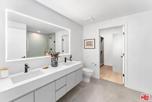 a bathroom with 2 sink toilet and a mirror