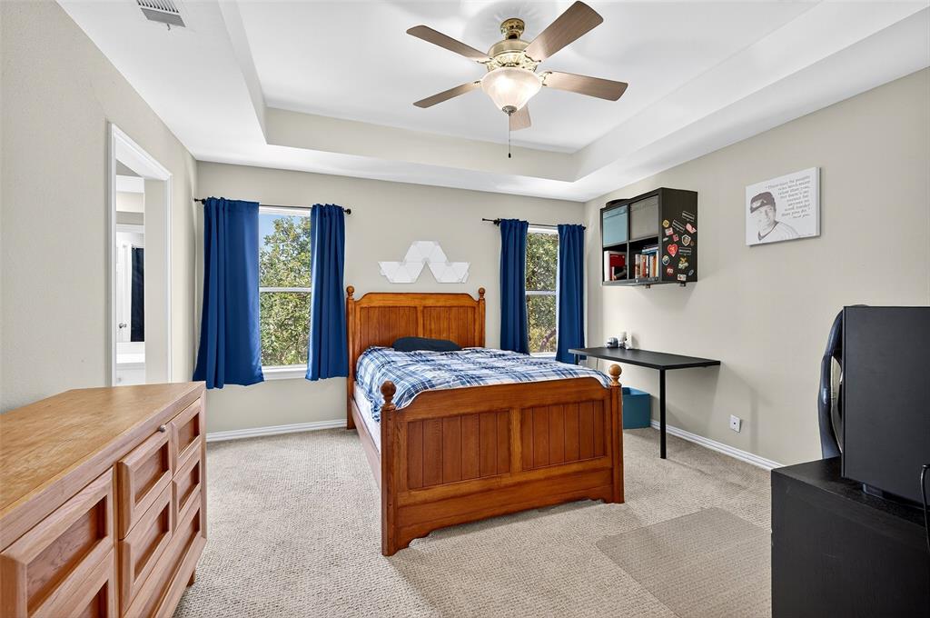 10312 Arvin Hill Road Aubrey, TX 76227 - Photo 32 of 40 a bedroom with a large bed and a chandelier