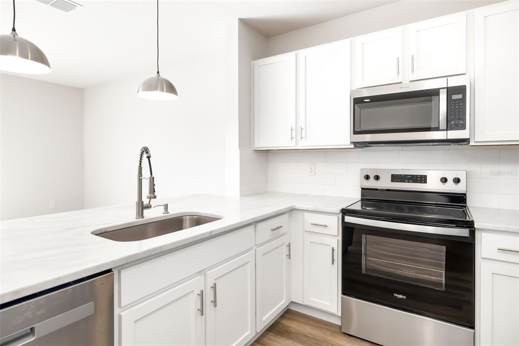 17436 Haysack Terrace Bradenton, FL 34211 - Photo 11 of 53 a kitchen with stainless steel appliances a stove a microwave and sink