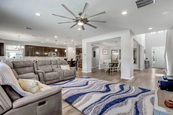 a living room with couches a dining table and kitchen view with wooden floor