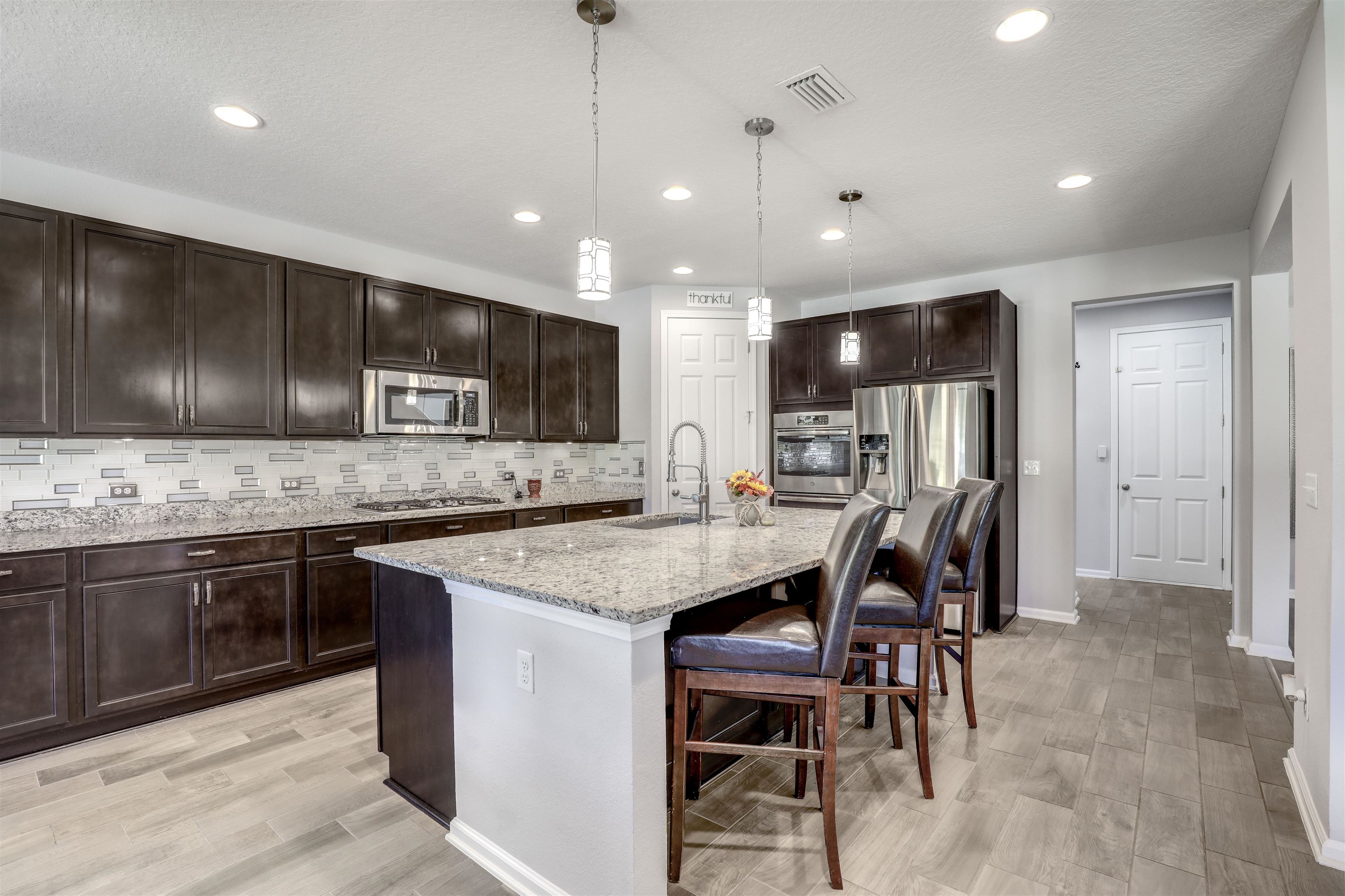 93 Firefly Trace St. Augustine, FL 32092 - Photo 4 of 76 a kitchen with stainless steel appliances kitchen island granite countertop a sink a stove a dining table and chairs