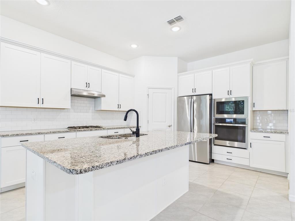 2033 Emerald Springs Drive Apopka, FL 32712 - Photo 12 of 49 a kitchen with granite countertop a sink stove and refrigerator