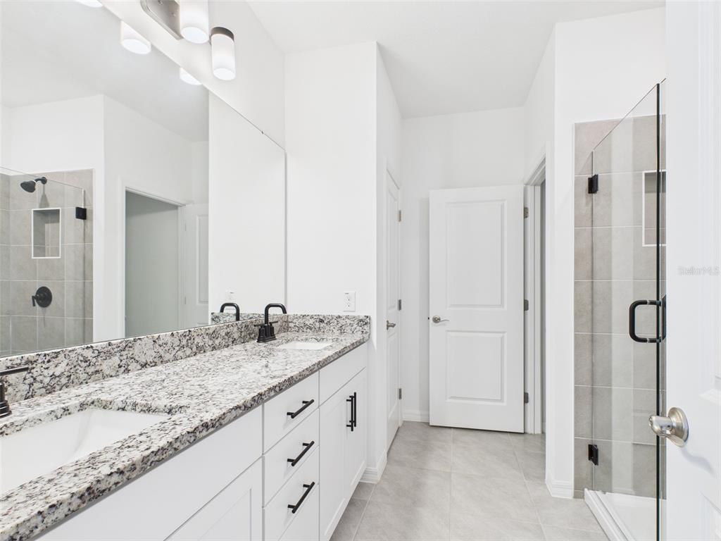 2033 Emerald Springs Drive Apopka, FL 32712 - Photo 35 of 49 a bathroom with a granite countertop sink two mirror and shower