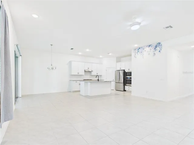 a large kitchen with kitchen island a sink a stove a refrigerator and black cabinets next to a window