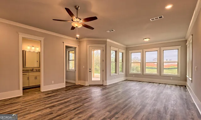 a view of an empty room with a window and wooden floor