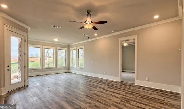 a view of an empty room with wooden floor and a window