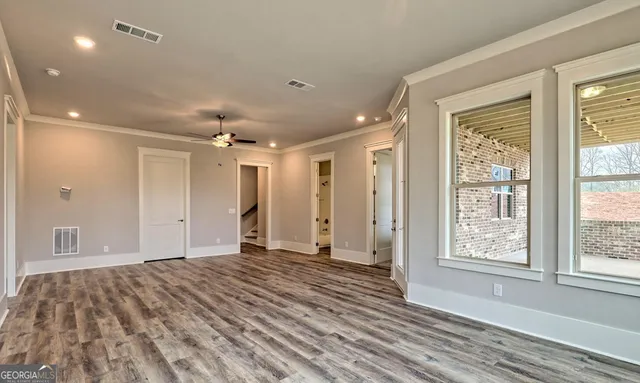 an empty room with a chandelier fan and windows