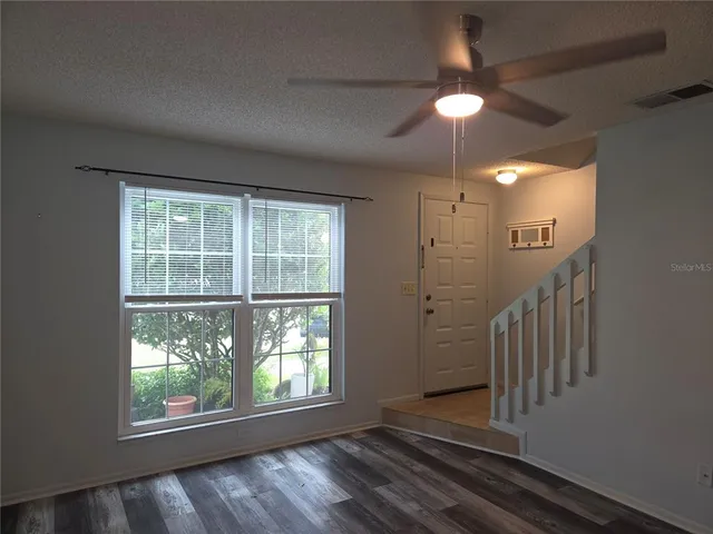 an empty room with wooden floor fan and windows