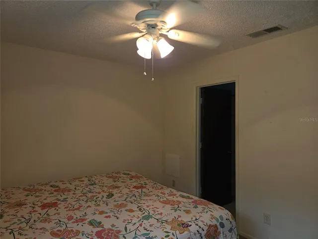a bedroom with a bed and a chandelier fan