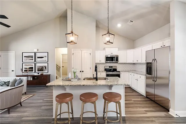 a kitchen with granite countertop a table chairs stove a refrigerator and cabinets