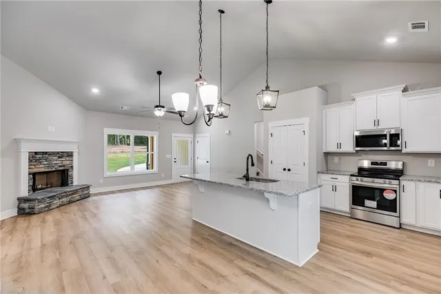 a kitchen with kitchen island a stove a sink a microwave and wooden floor