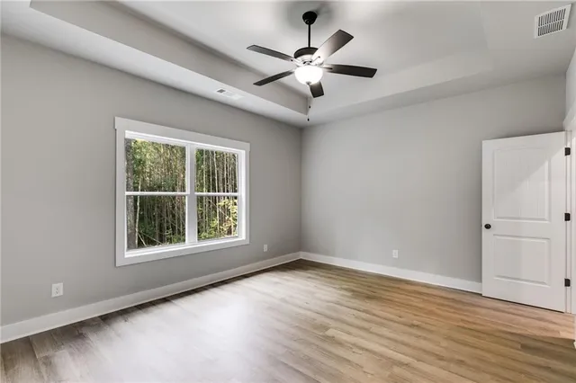 an empty room with wooden floor chandelier ceiling fan and windows