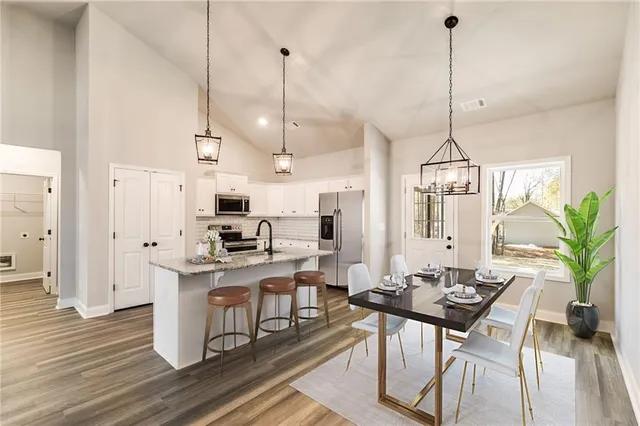 a view of a dining room and livingroom with furniture wooden floor a chandelier