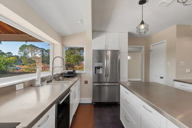 a kitchen with stainless steel appliances granite countertop a refrigerator a sink dishwasher a oven a dining table and chairs with wooden floor