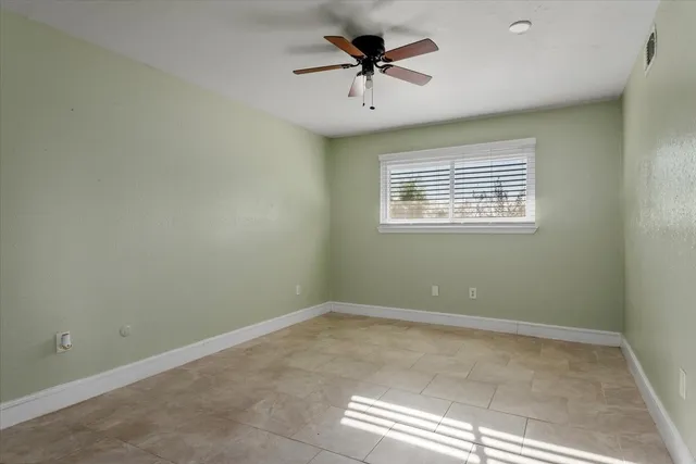 an empty room with a window and a ceiling fan