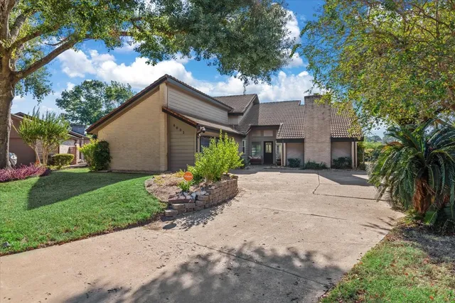 a view of a house with a small yard and a large tree