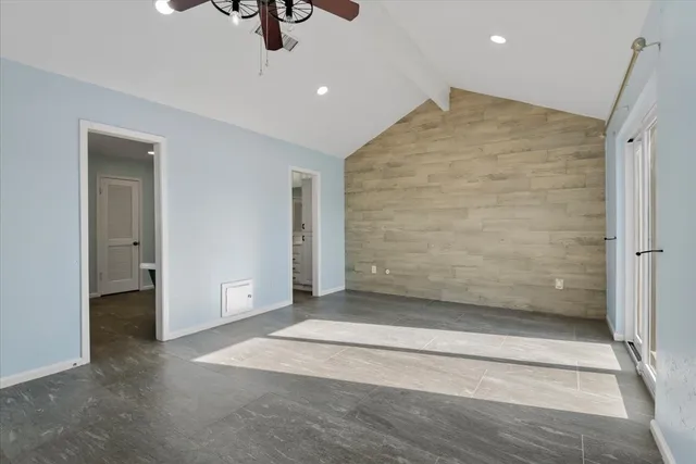 an empty room with ceiling fan and windows