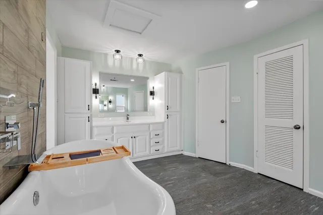 a spacious bathroom with a tub sink and mirror