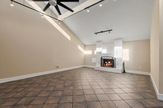 an empty room with windows and fireplace