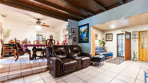 a living room with lots of white furniture a chandelier fan and a rug