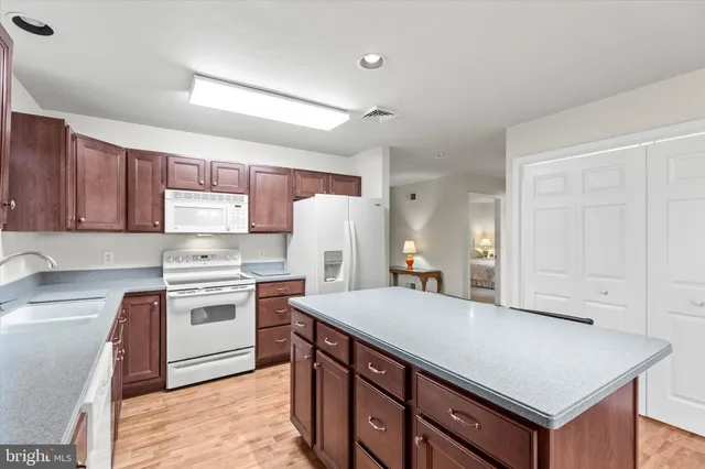 a kitchen with stainless steel appliances a sink a stove a refrigerator cabinets and a center island